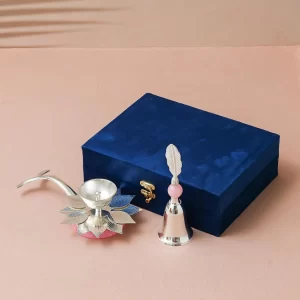Silver diya gift set with lotus design, bell and decorative pooja accessories in a velvet box